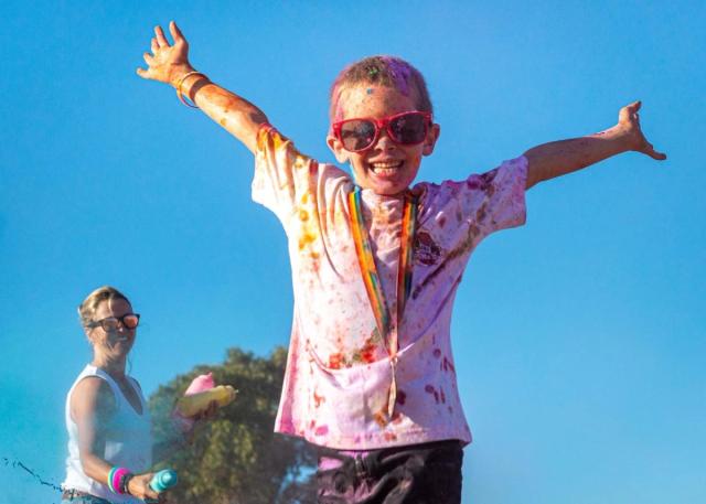 Boy covered in paint, big smiles and wearing his medallion 