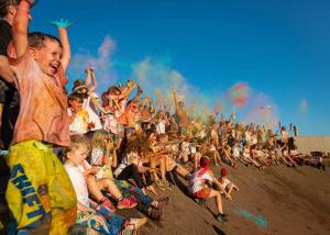 Kids covered in rainbow colours cheering together 