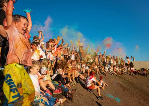 Kids covered in rainbow colours cheering together 