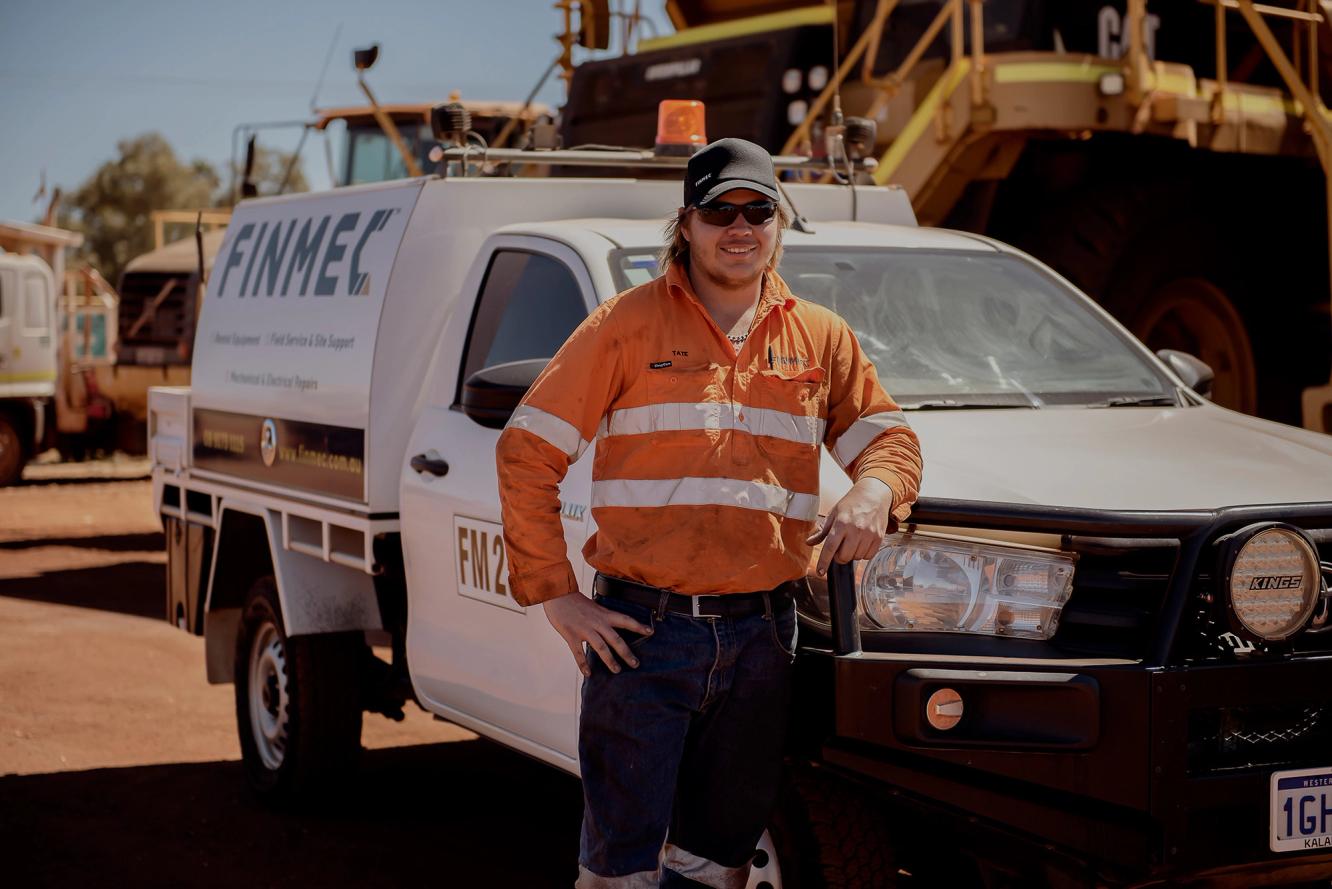 Tate from Finmec smiling whilst leaning on his service vehicle 
