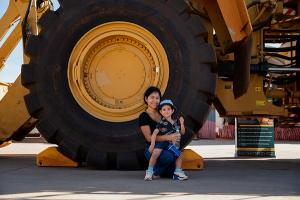 Mother and Son sitting against a cat loaders wheel
