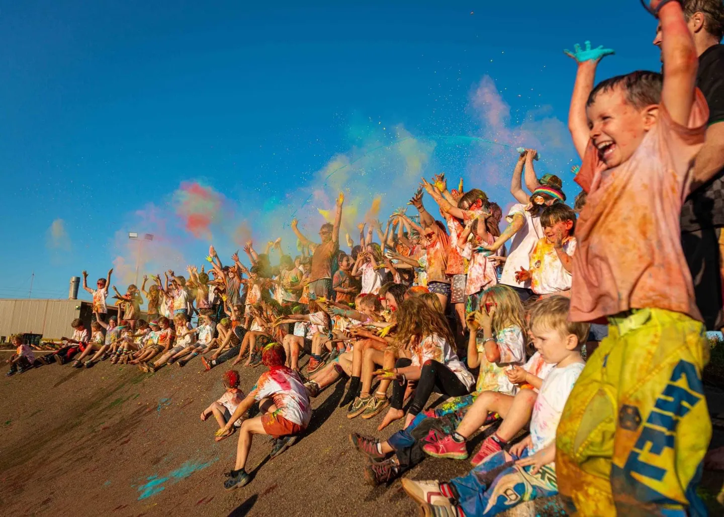 Kids covered in coloured paint all cheering and smiling