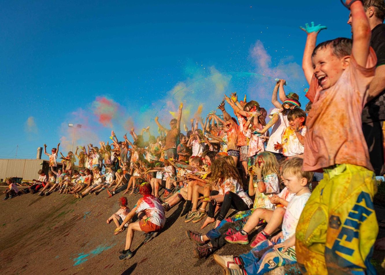 Kids covered in coloured paint all cheering and smiling